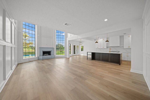 unfurnished living room featuring a textured ceiling and light hardwood / wood-style flooring