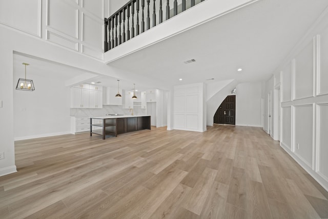 unfurnished living room with a towering ceiling and light wood-type flooring