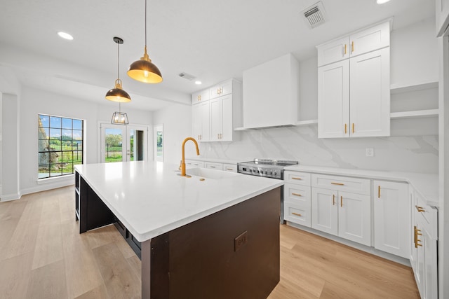 kitchen with backsplash, light hardwood / wood-style floors, white cabinetry, and sink