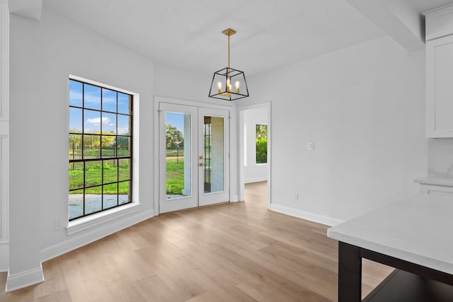 unfurnished dining area featuring a chandelier and light wood-type flooring