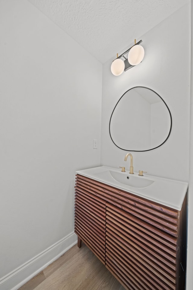 bathroom with hardwood / wood-style floors, vanity, and a textured ceiling