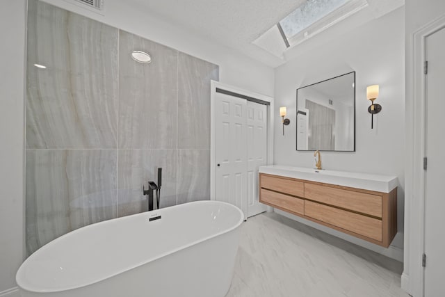 bathroom with a washtub, vanity, and a skylight