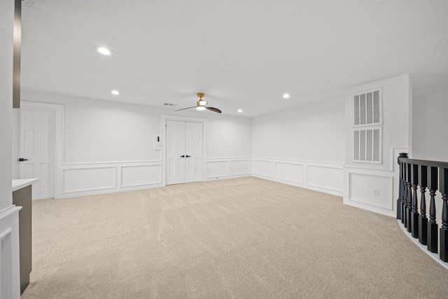 empty room featuring ceiling fan and light colored carpet