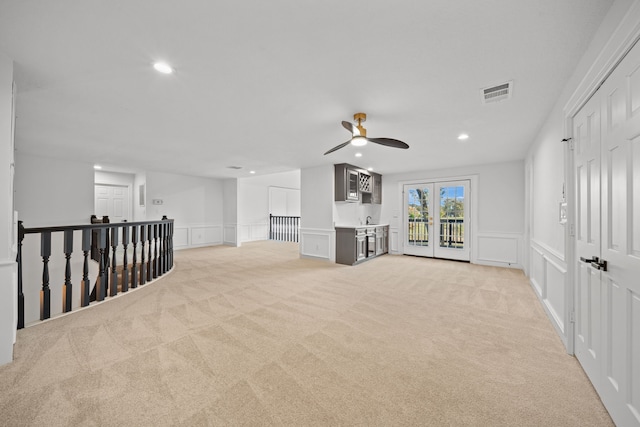 unfurnished living room with ceiling fan, light carpet, and french doors