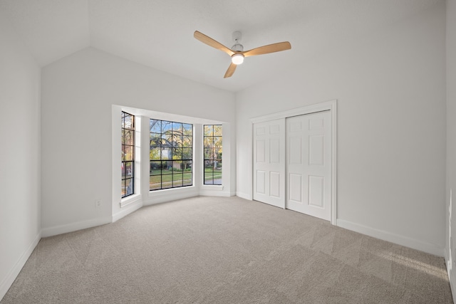 unfurnished bedroom with carpet, a closet, lofted ceiling, and ceiling fan