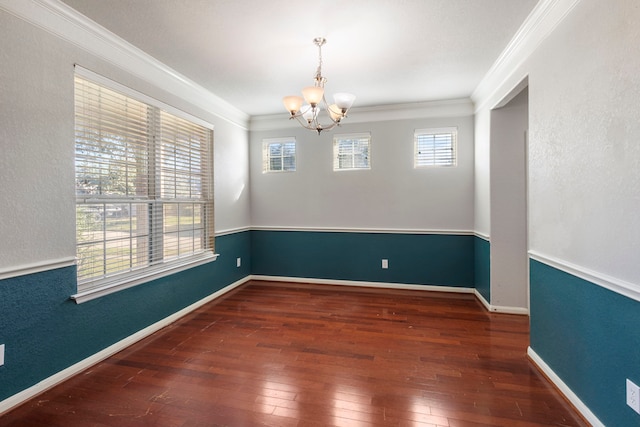 empty room featuring dark hardwood / wood-style floors, crown molding, and a notable chandelier