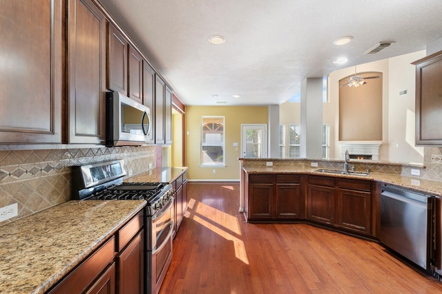 kitchen featuring light stone countertops, stainless steel appliances, tasteful backsplash, sink, and hardwood / wood-style flooring