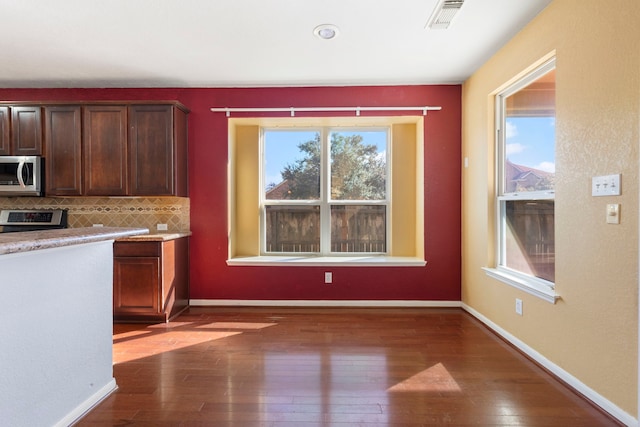 kitchen with tasteful backsplash, appliances with stainless steel finishes, and dark wood-type flooring