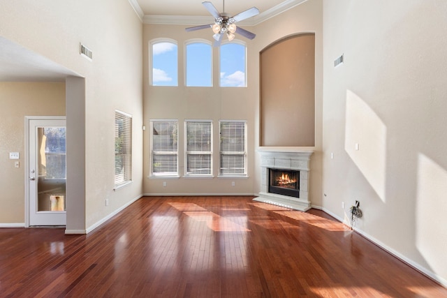 unfurnished living room with ceiling fan, a high ceiling, wood-type flooring, and ornamental molding