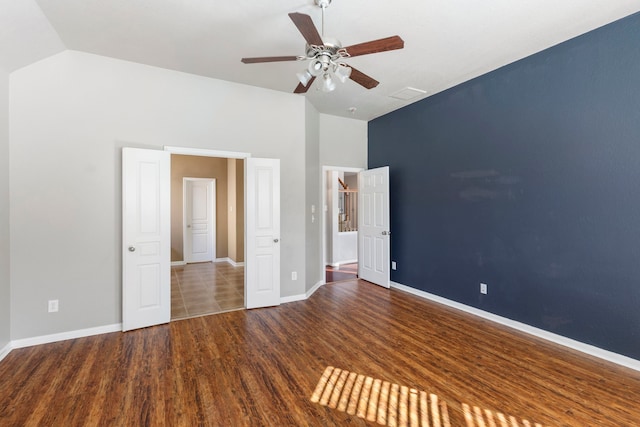 unfurnished bedroom featuring ceiling fan, vaulted ceiling, and dark hardwood / wood-style flooring