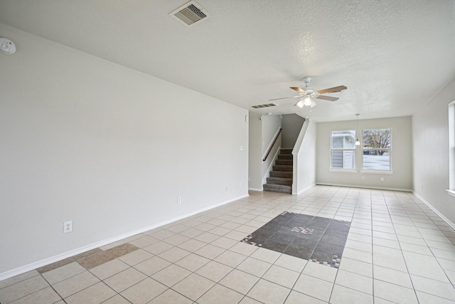 spare room featuring ceiling fan, light tile patterned floors, and a textured ceiling