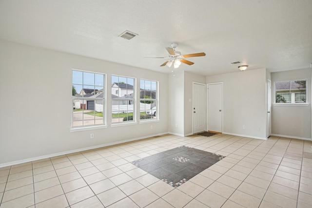 empty room with ceiling fan, light tile patterned floors, and a textured ceiling