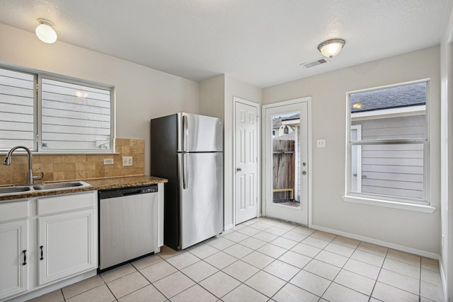 kitchen with decorative backsplash, stainless steel appliances, sink, white cabinets, and light tile patterned flooring