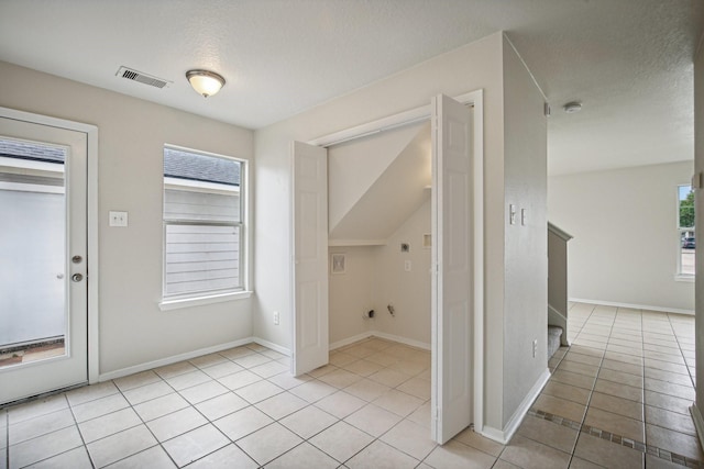 hall featuring light tile patterned floors and a textured ceiling