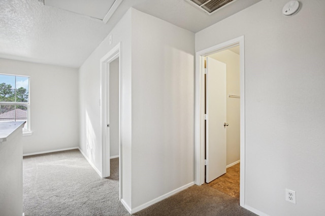 hallway featuring carpet and a textured ceiling