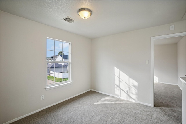 carpeted empty room featuring a textured ceiling