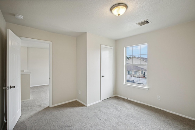 unfurnished bedroom with light colored carpet, a textured ceiling, and a closet