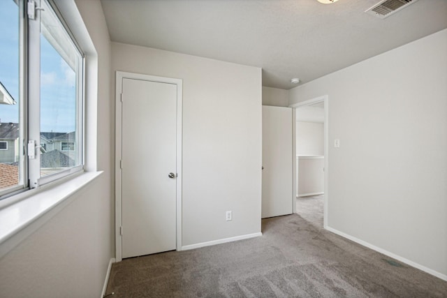 unfurnished bedroom with light colored carpet and multiple windows