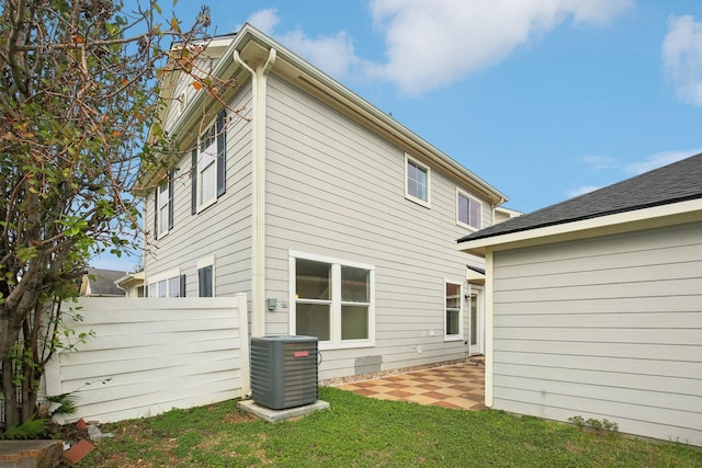 rear view of house featuring a yard, cooling unit, and a patio area