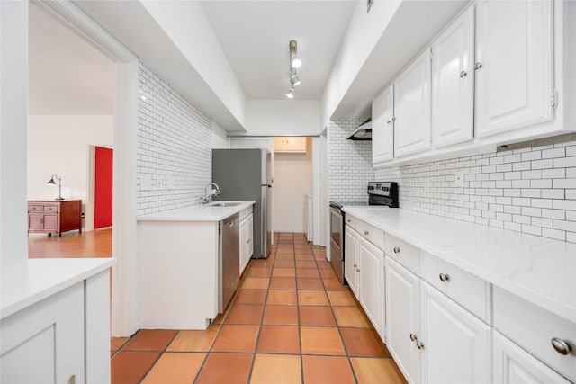 kitchen with backsplash, white cabinets, sink, light tile patterned floors, and appliances with stainless steel finishes