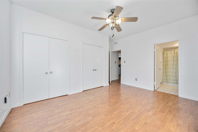 unfurnished bedroom featuring connected bathroom, ceiling fan, light hardwood / wood-style flooring, and multiple closets