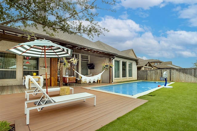 view of swimming pool featuring a deck, a yard, fence, and a fenced in pool