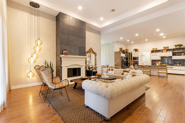 living room featuring recessed lighting, baseboards, wood finished floors, and a tile fireplace