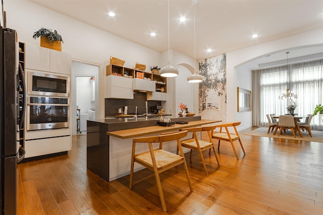 kitchen featuring appliances with stainless steel finishes, white cabinets, decorative light fixtures, and open shelves