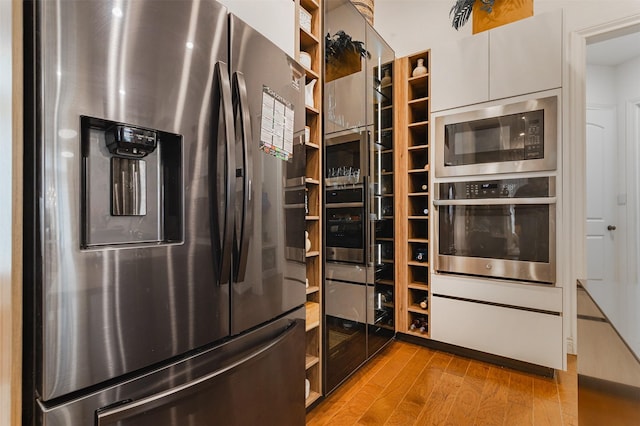 kitchen featuring white cabinets, light wood-style flooring, modern cabinets, appliances with stainless steel finishes, and open shelves