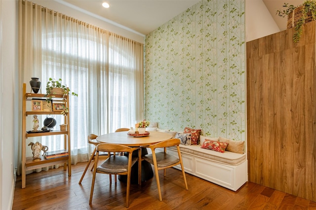 dining area featuring wood finished floors and wallpapered walls