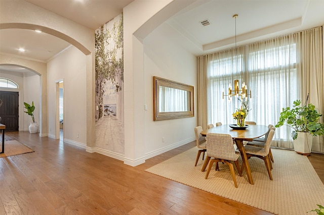 dining space featuring an inviting chandelier, a tray ceiling, and wood finished floors