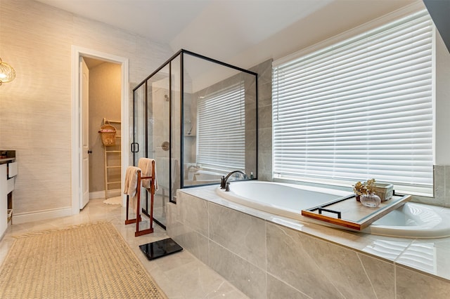 full bath with a stall shower, a healthy amount of sunlight, a garden tub, and baseboards