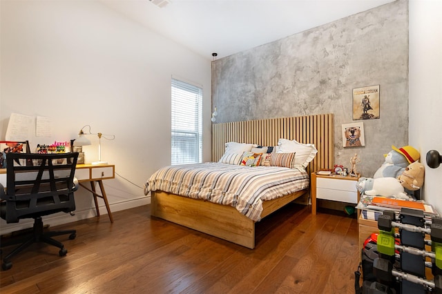 bedroom featuring dark wood-style floors, an accent wall, and baseboards