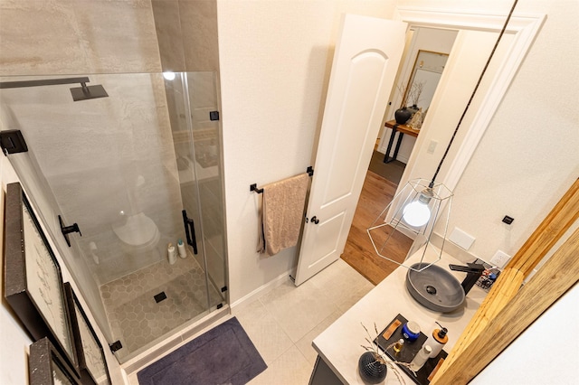 bathroom featuring tile patterned flooring, a sink, a shower stall, and baseboards