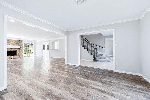 unfurnished living room with a large fireplace, hardwood / wood-style flooring, and crown molding