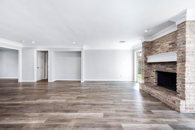 unfurnished living room with hardwood / wood-style flooring, crown molding, and a brick fireplace