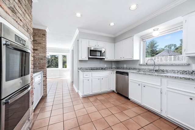 kitchen with appliances with stainless steel finishes, white cabinetry, plenty of natural light, and sink