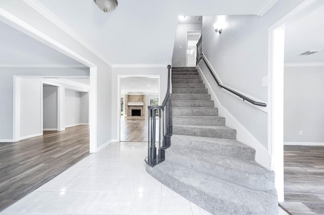 stairs featuring a fireplace, hardwood / wood-style floors, and ornamental molding