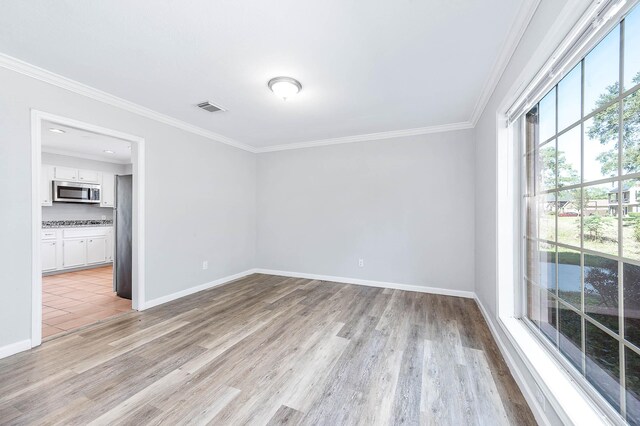 empty room with crown molding and light hardwood / wood-style floors