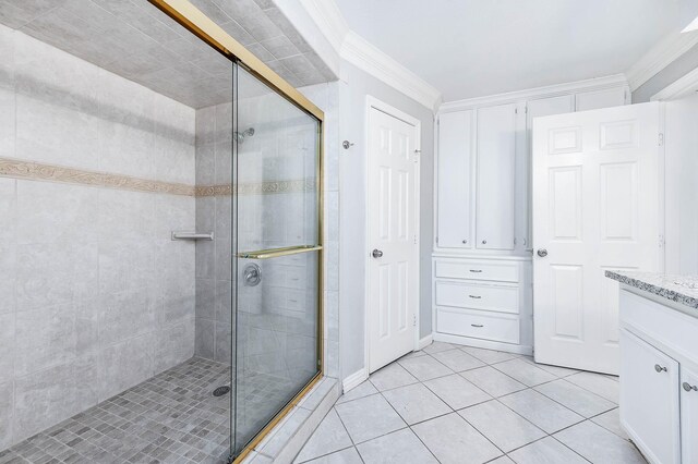 bathroom with tile patterned flooring, vanity, a shower with door, and crown molding