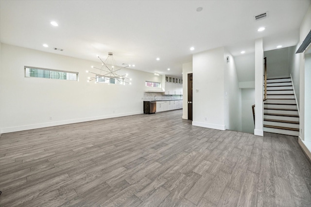 unfurnished living room featuring light wood-type flooring and an inviting chandelier