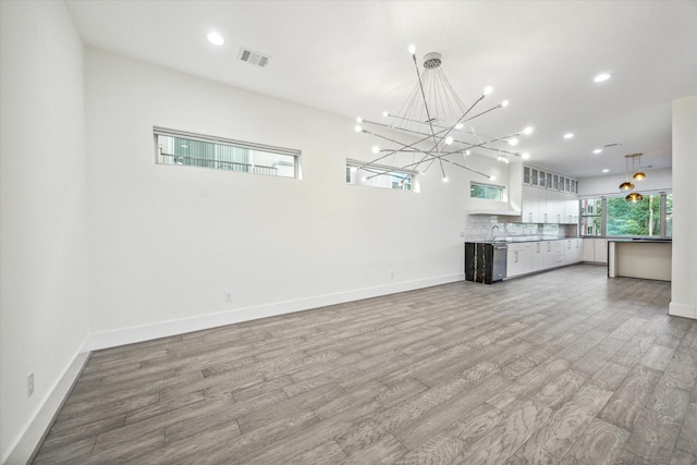 unfurnished living room featuring wood-type flooring and an inviting chandelier