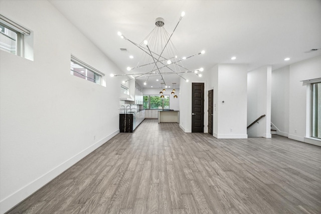 unfurnished living room featuring hardwood / wood-style floors, a high ceiling, and sink