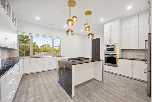 kitchen with white cabinets, appliances with stainless steel finishes, backsplash, and decorative light fixtures