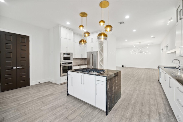 kitchen featuring decorative backsplash, white cabinets, hanging light fixtures, and appliances with stainless steel finishes