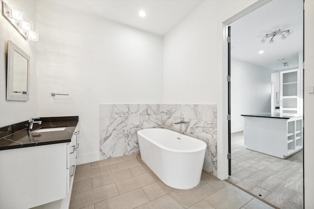 bathroom with a washtub, tile walls, and vanity