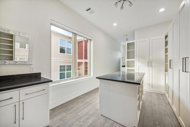 kitchen featuring white cabinets, a kitchen island, light hardwood / wood-style floors, and a wealth of natural light