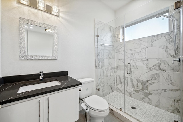 bathroom featuring a shower with door, vanity, and toilet