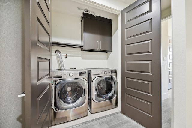 clothes washing area featuring cabinets and separate washer and dryer