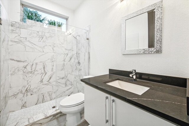 bathroom featuring vanity, toilet, and a tile shower